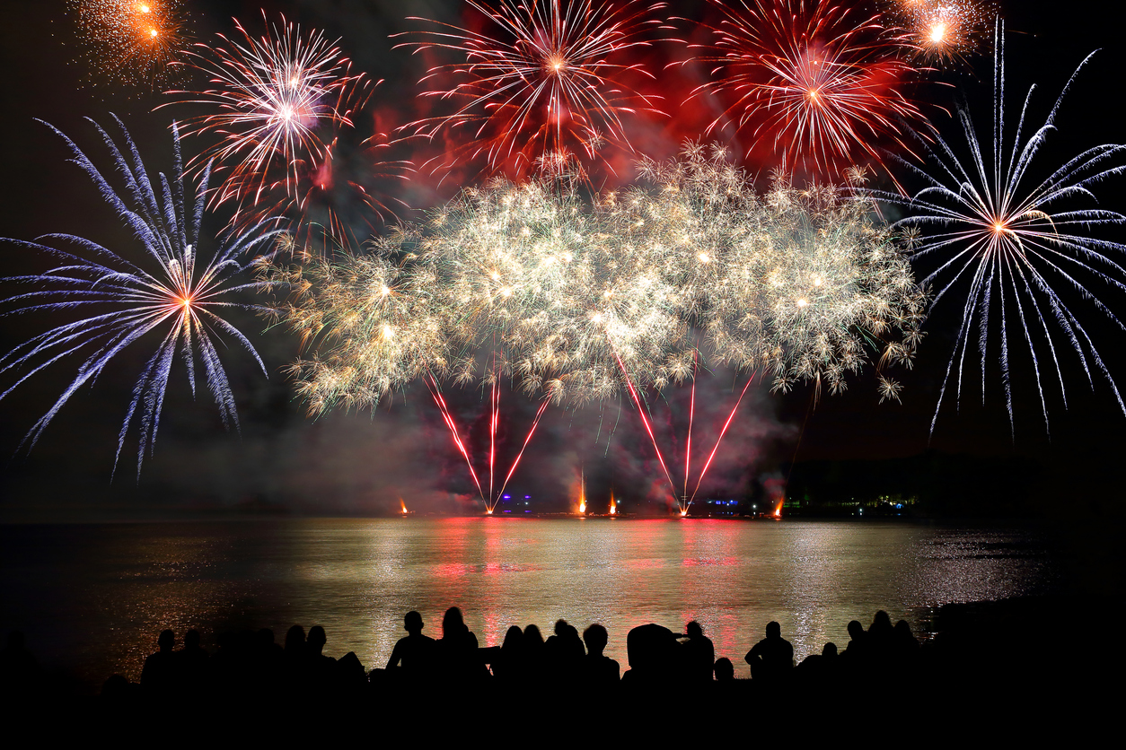 Crowd watching a firework display over a body of water