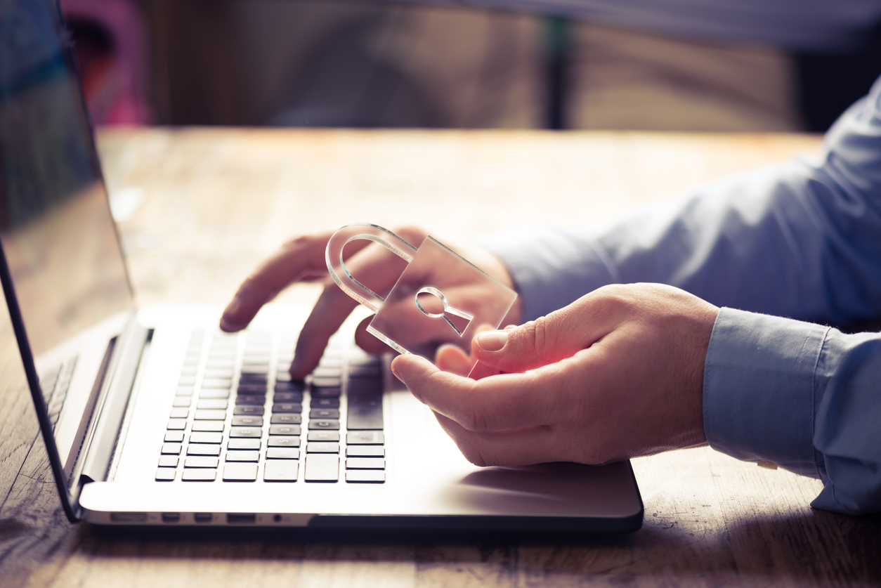 Someone holding a clear lock and typing on a laptop